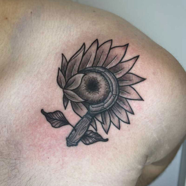 atticus tattoo, black and grey neotraditional tattoo of a sickle and sunflower