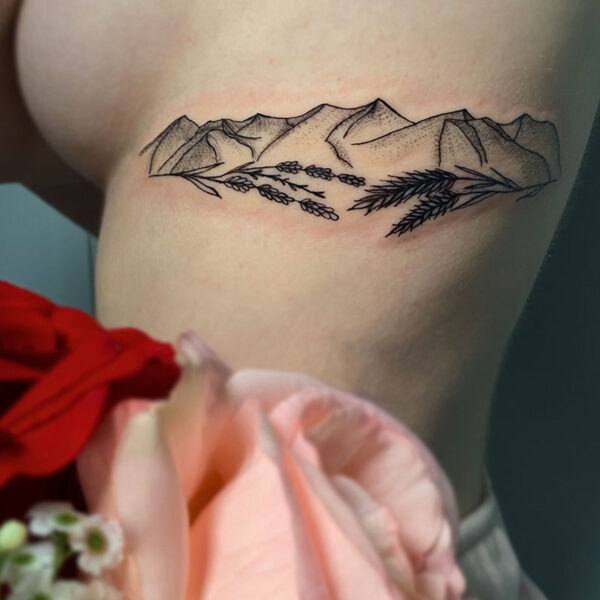atticus tattoo, fine line tattoo of a mountain range with stalks of wheat and lavender framing the bottom of the mountains