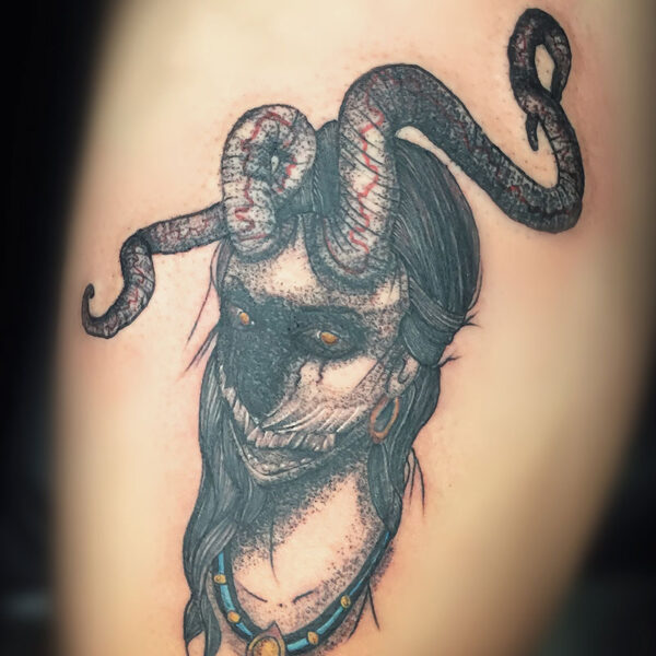 atticus tattoo, black and grey tattoo of a demon woman with twisted horns, sharp teeth red eyes and her face mostly blacked out face