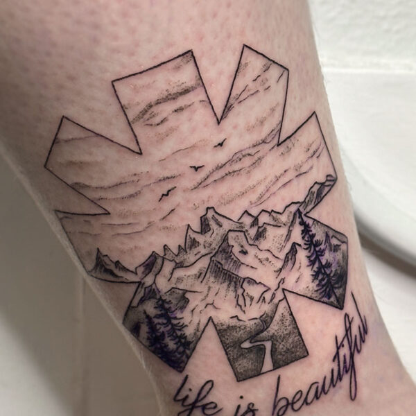 atticus tattoo, black and grey tattoo of the star of life with a mountain scene inside and the quote "life is beautiful"