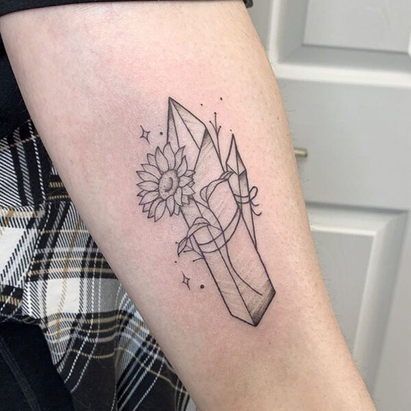 atticus tattoo, black and grey tattoo of crystals with a sunflower tied around them