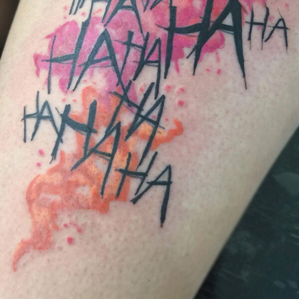 atticus tattoo, tattoo of "HAHAHA" wrote multiple times with pink and orange splatter behind the text
