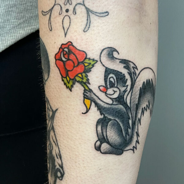 atticus tattoo, American traditional tattoo of a skunk holding a rose
