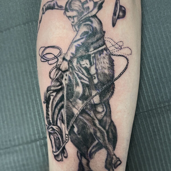 atticus tattoo, black and grey realism tattoo of a cowboy riding a bucking horse