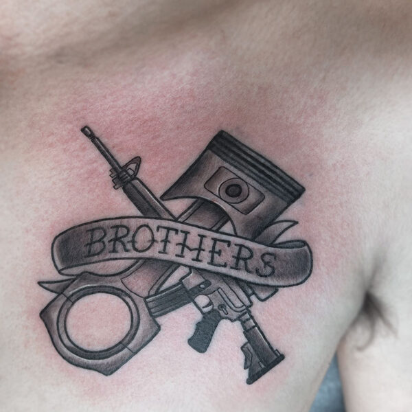 atticus tattoo, black and grey neotraditional tattoo of cigar cutter and machine gun with a ribbon that says brothers