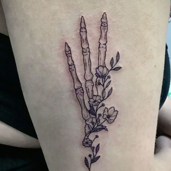 atticus tattoo, black and grey tattoo of three skeleton fingers and a vine of flowers
