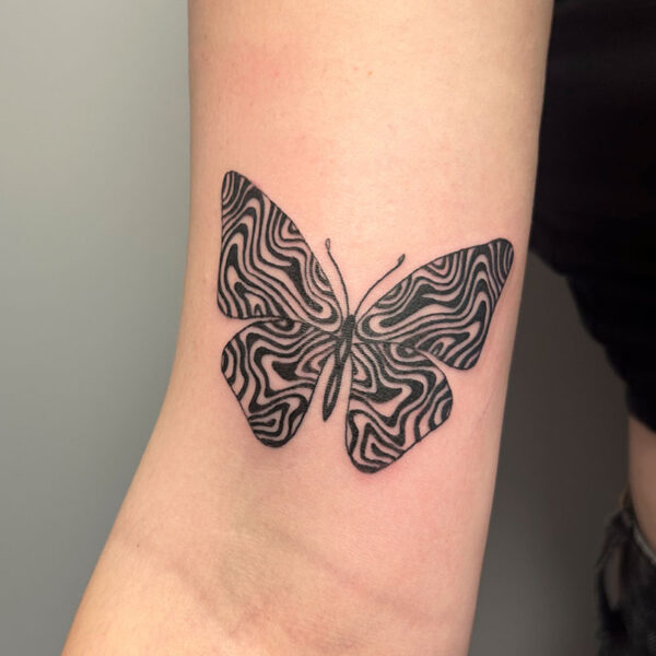 atticus tattoo, black tattoo of a butterfly with a swirled pattern in the wings