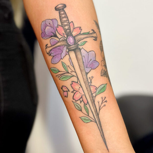 Tattoo of a black and grey dagger with purple and orange flowers