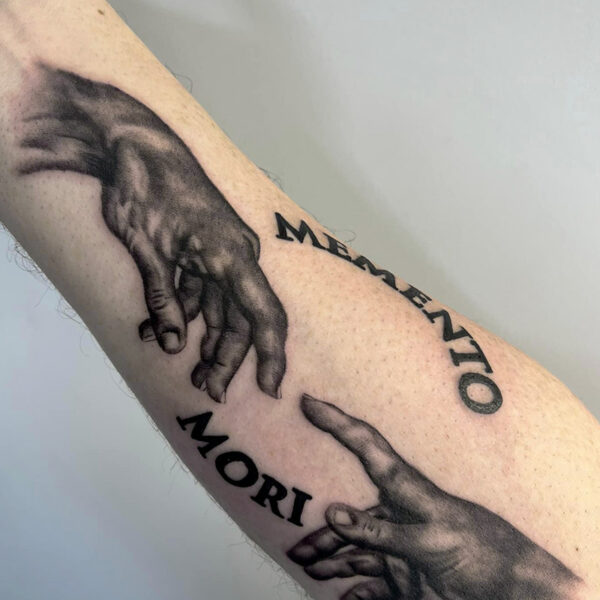 Atticus Tattoo| Black and grey, realism tattoo of the hands from "The Creation of Adam" with the words "Memento Mori"