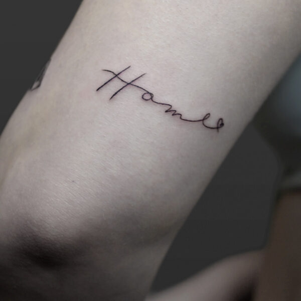 Atticus Tattoo| Fine line, script tattoo of the word "Home"