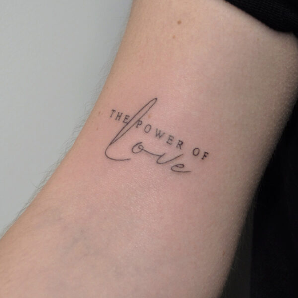 Atticus Tattoo| Fine line, script tattoo of the words "The Power of Love"