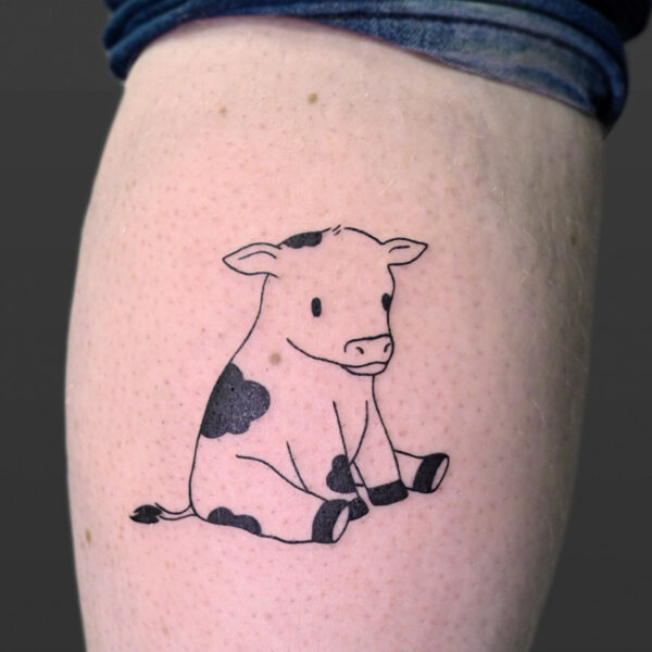 Atticus Tattoo| Fine line tattoo of a spotted cow that sitting on it's hind legs