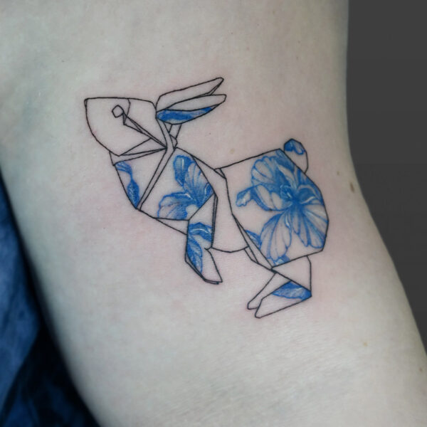 Atticus Tattoo| Fine line tattoo of an origami bunny with blue flowers