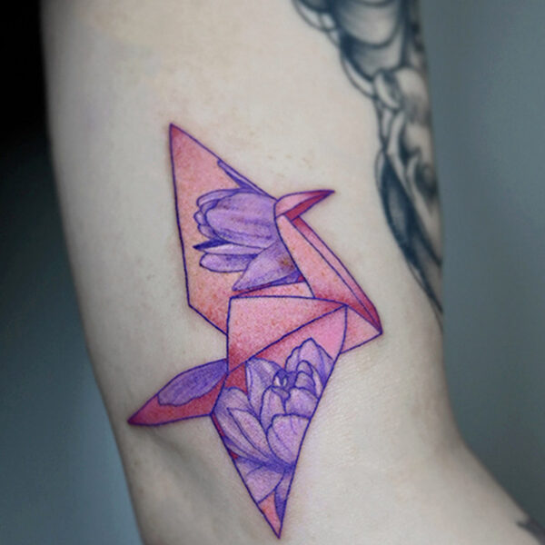 Atticus Tattoo| Fine line tattoo of a pink origami crane and purple flowers