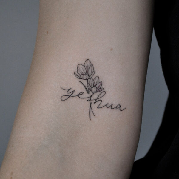 Atticus Tattoo| Fine line tattoo of flowers with a signature