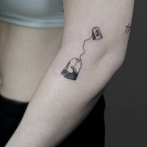 Atticus Tattoo| Fine line tattoo of a tea bag with a wave inside it