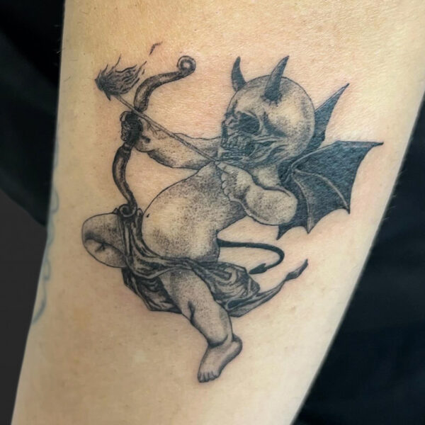 Atticus Tattoo| Black and grey tattoo of a cupid with a skull face, devil horns and bat wings