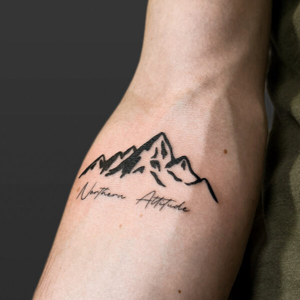 Atticus Tattoo| Blackwork tattoo of a mountain range with fine line, script tattoo that says "Northern Attitude"