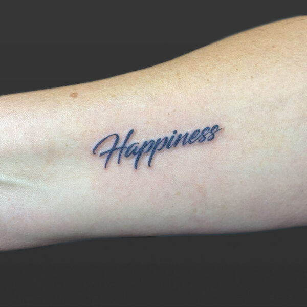 Atticus Tattoo| Script tattoo of the word "Happiness"