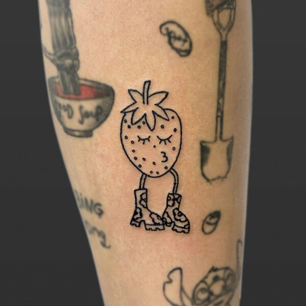 Atticus Tattoo| Small tattoo of a strawberry with a kissing face and wearing shoes