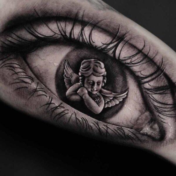 Atticus Tattoo| Black and grey realism tattoo of an eyeball with a reflection of a cherub in the pupil