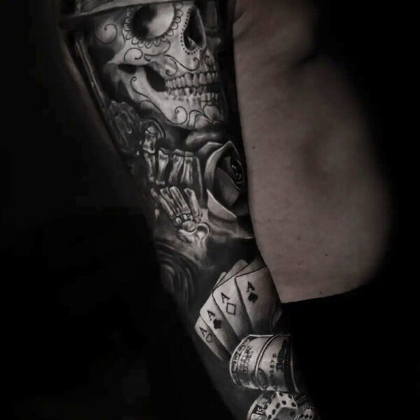 Atticus Tattoo| Black and grey realism tattoo of sugar skull skeleton holding a gun, with cards, cash and poker chips