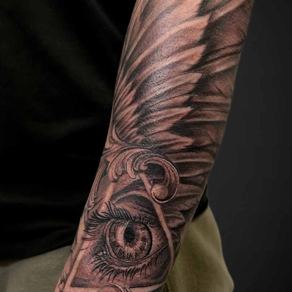 Black and Grey Realism Tattoo- Eye and Wing Atticus Tattoo| Black and grey realism tattoo of an eye, framed by a triangle and a bird wing