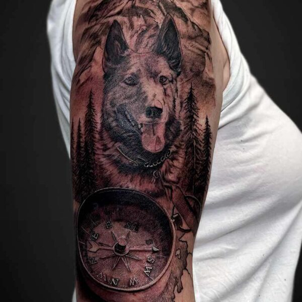 Black and Grey Realism Tattoo- Dog and Mountains Atticus Tattoo| Black and grey realism tattoo of a German Shepard with a compass and mountains