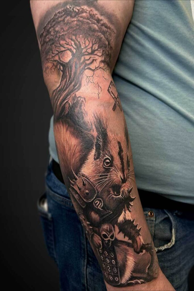 Atticus Tattoo| Black and grey realism tattoo of a squirrel in viking armour with a tree behind it