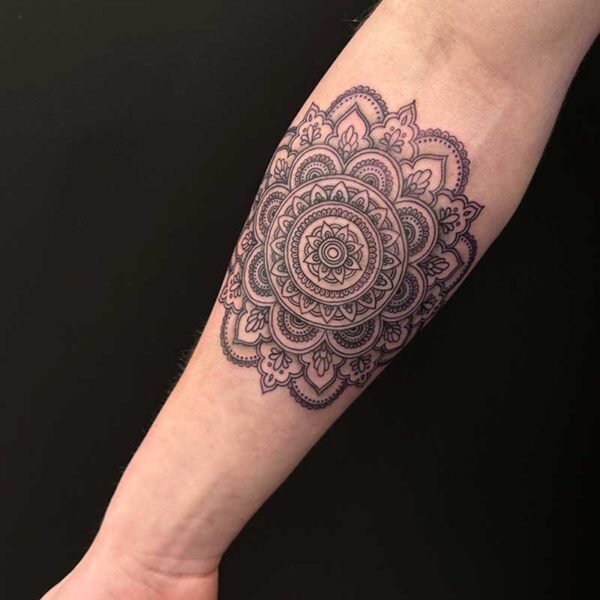 Forearm with an intricate black mandala tattoo wrapping around the lower forearm.