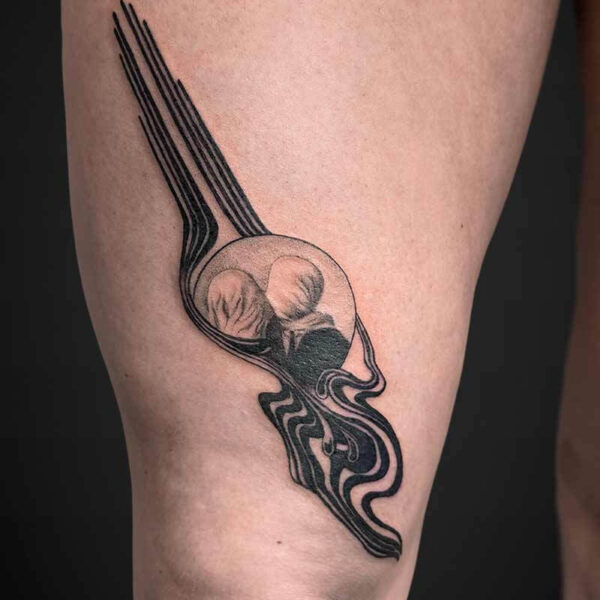 Black line-work tattoo of a stylized fork with three long tines and flowing decorative curves along a person's leg.