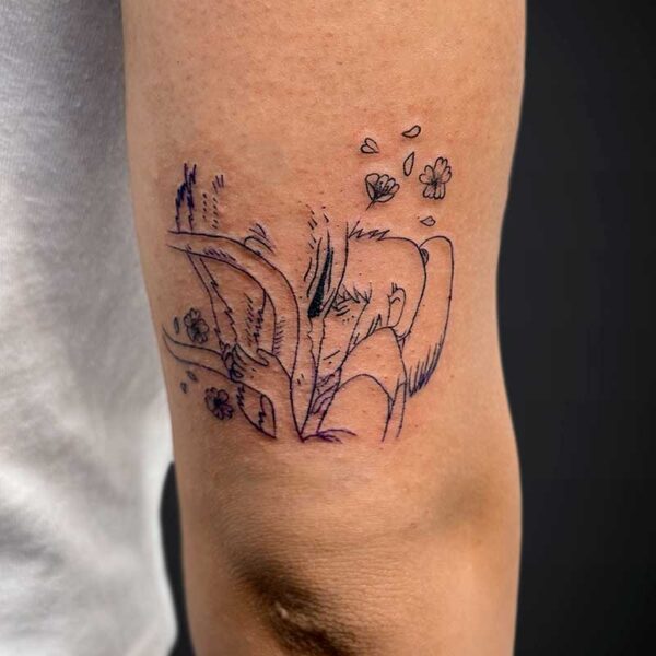 Thin black line tattoo on inner forearm of a tree or branch design with small blossoms and petals drifting away on the skin.