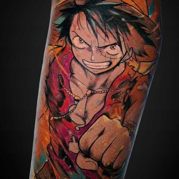 Colorful tattoo of Luffy from One Piece, wearing his straw hat and pointing forward with a determined grin inside a vibrant background.