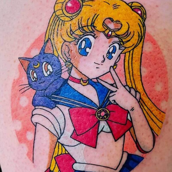 Sailor Moon tattoo featuring the character with blue eyes and long blond pigtails, posing with a peace sign and a blue Luna cat on her shoulder