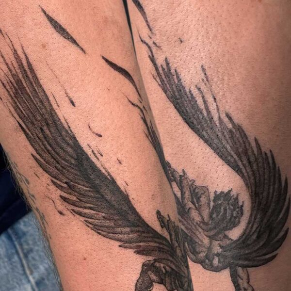 Black and gray wing tattoo wrapping around the forearm, feathers spread.