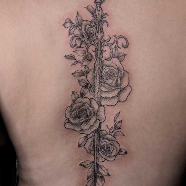 Back view of a vertical sword tattoo running along the spine, with ornate hilt and intertwined roses along the blade