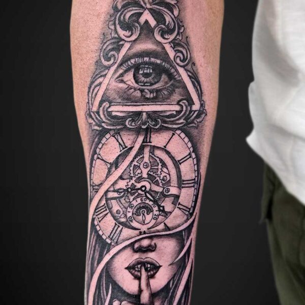 Tattoo on forearm: an eye inside a triangular pyramid over a clockwork gear, with a veiled face and finger to lips in a Shh gesture.
