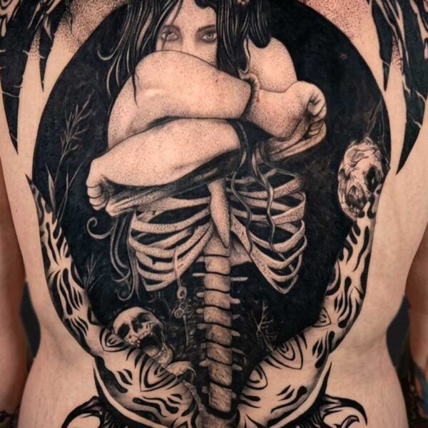 Back tattoo showing a curled woman inside a dark circular frame, with an exposed ribcage and skulls around the edges.
