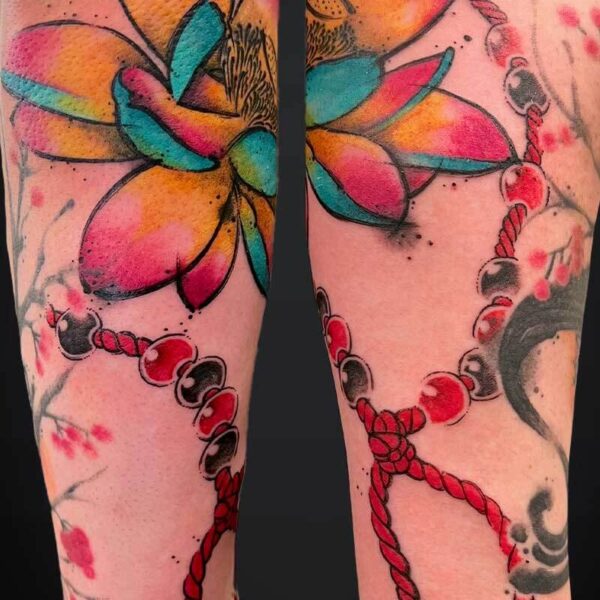 Colorful butterfly tattoo across both forearms with a red beaded rope design wrapping around the arms.