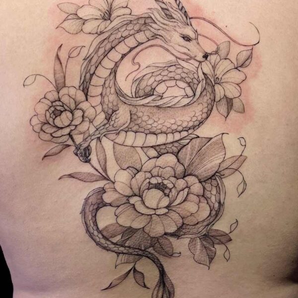 Back tattoo of a serpentine dragon entwined with large flowers and leaves, detailed line work and shading.