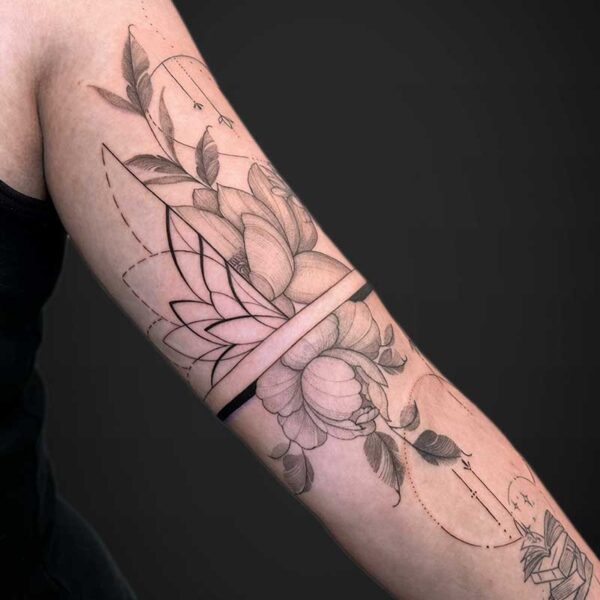 Forearm tattoo with a large flower and geometric linework, including dotted curves.