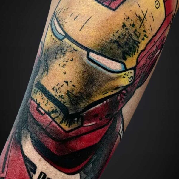 Close-up tattoo of Iron Man helmet in red and gold on an arm, with bold black outlines and shading.