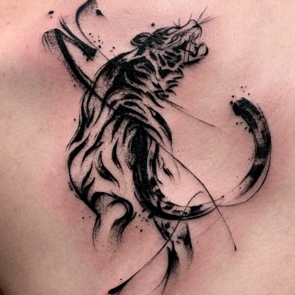 Stylized black ink tiger tattoo on the shoulder with sweeping brush strokes and splatter shading.
