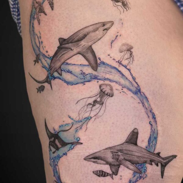 Tattoo on the leg: a blue spiral wave with a large shark and several jellyfish around it.