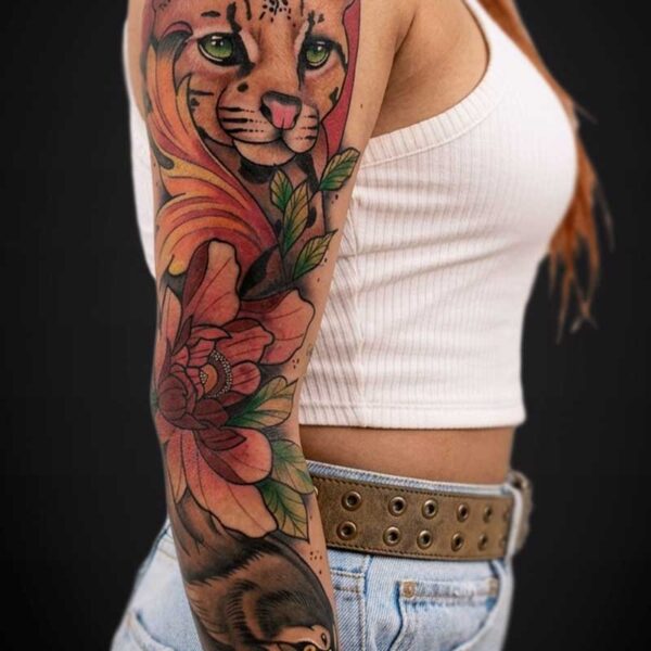 Colorful tattoo sleeve on a woman's upper arm: tiger head with green eyes, pink flowers, and a snarling animal lower on the forearm.