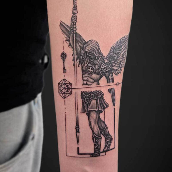Forearm tattoo with a tall cross and rope-wrapped shaft, beside a winged armored figure and geometric shapes in a bordered panel.