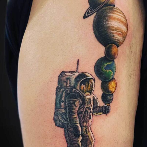 Colorful astronaut on the forearm holding a string of planets like a necklace.