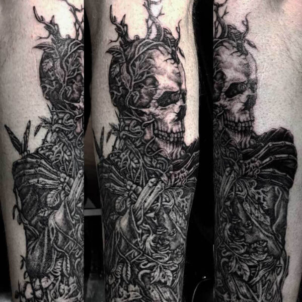 Forearm tattoo sleeve featuring a skeletal skull entwined with twisting vines and thorny branches, heavy black shading throughout
