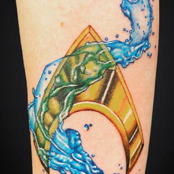 Colorful tattoo of a yellow-orange surfboard with a green pattern, surrounded by a blue splash-waves design.
