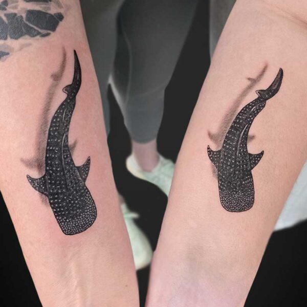 Pair of matching black stingray tattoos on each forearm with dotted shading.